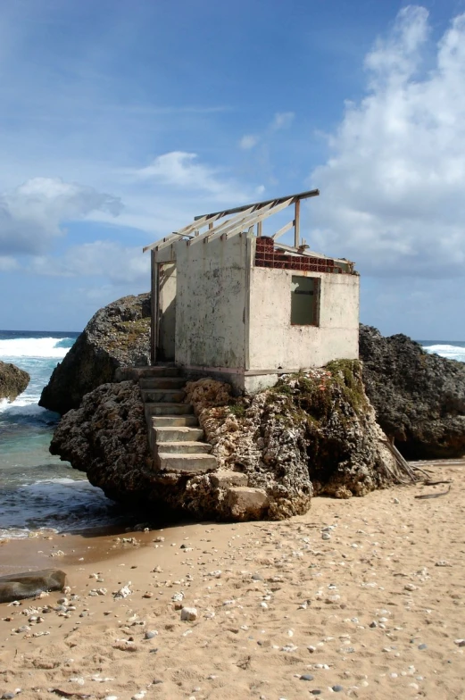 an abandoned fishing hut sitting on the shore of the beach