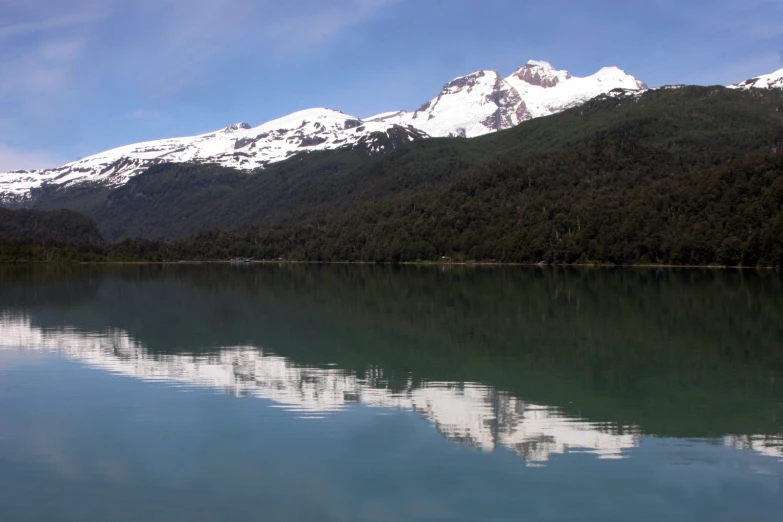 the mountains reflected in the lake are covered with snow