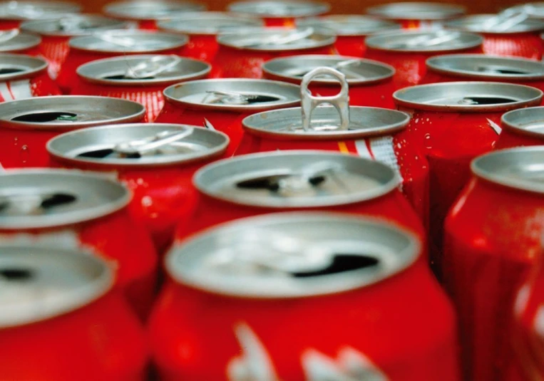 a stack of red soda cans with a metal snap lock on each one