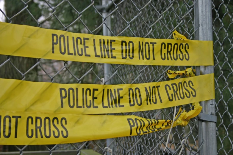 four yellow police signs next to barbed wire