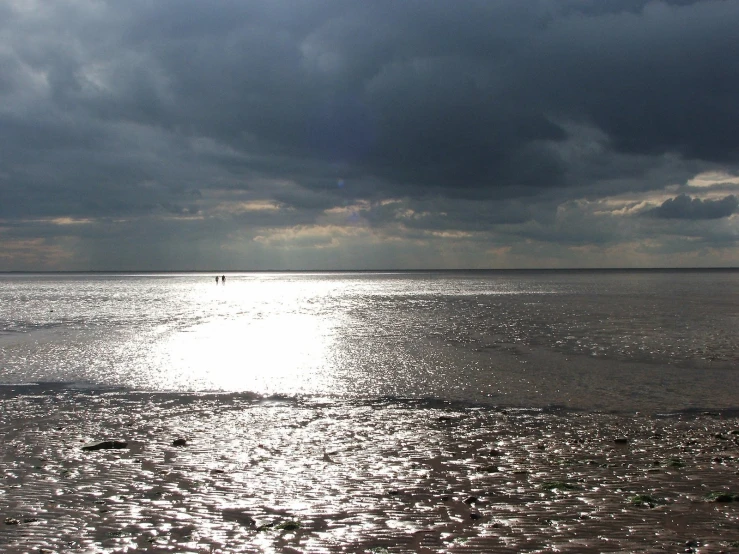 some people are surfing in the ocean on a cloudy day