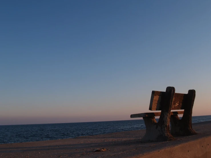 a wooden bench sitting in the middle of a beach