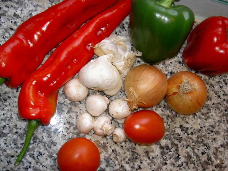 a group of ingredients including a pepper, onions and tomatoes on a counter top