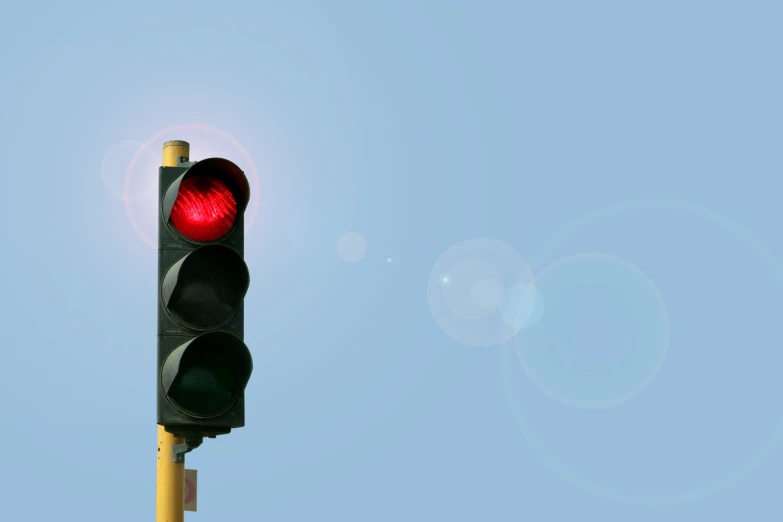 a red stop light with a bright blue sky