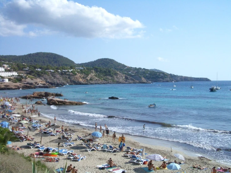 a sandy beach is crowded with people on a sunny day