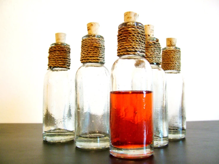 five empty bottles full of liquid sit on a table