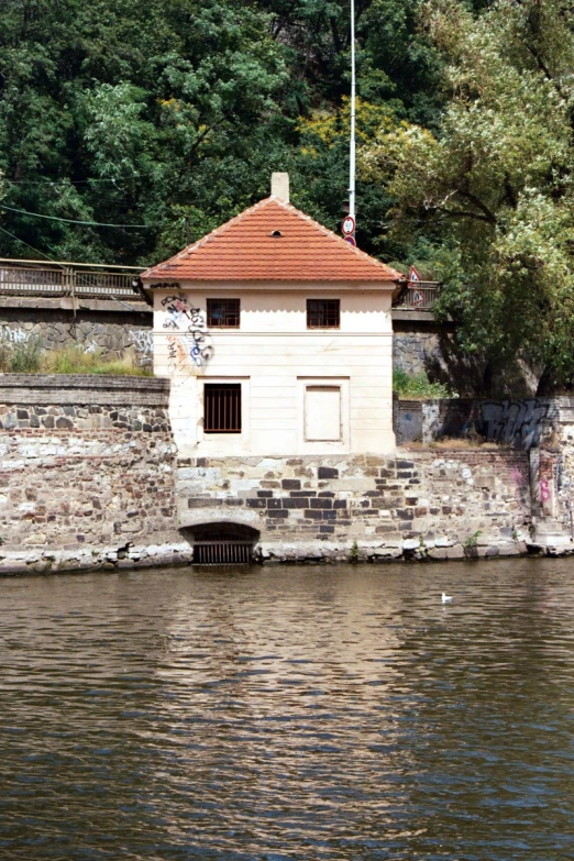 a stone building sitting on top of the side of a river