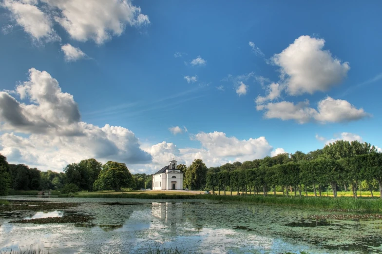 a white building sitting in the middle of trees next to a lake