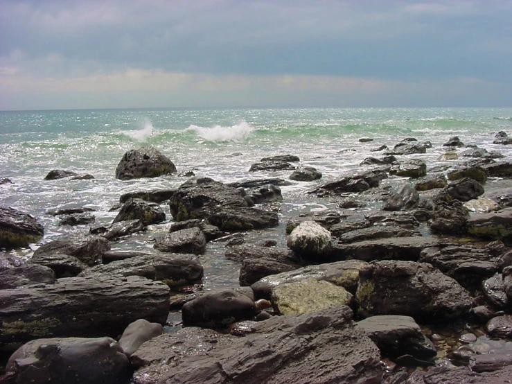 a rocky shoreline with small rocks and a body of water