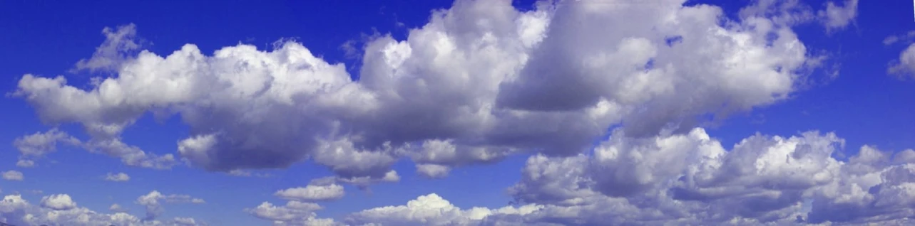 an airplane flying low with fluffy clouds in the sky