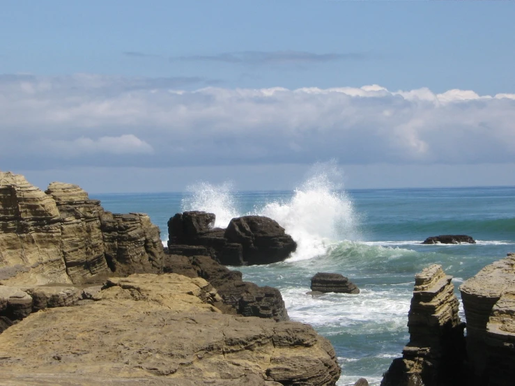 a wave hits against the rocky shoreline