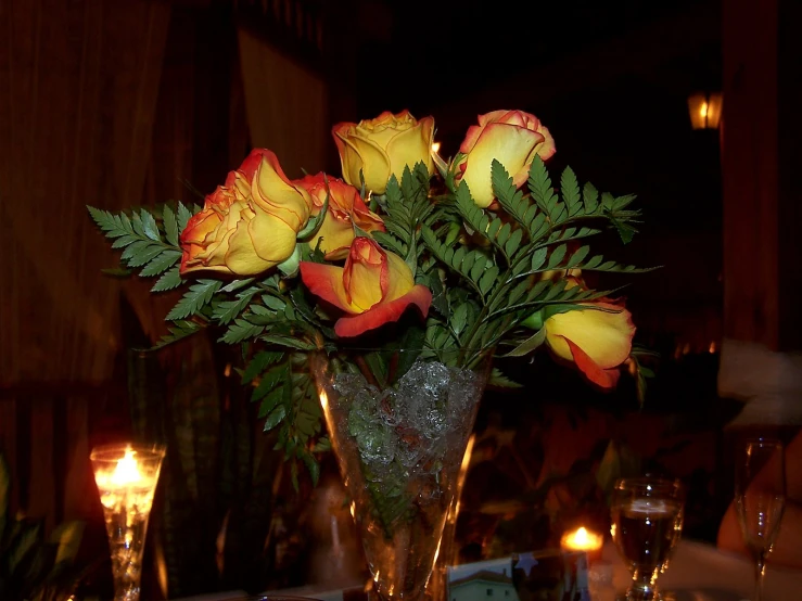 a vase filled with yellow and red roses on a table