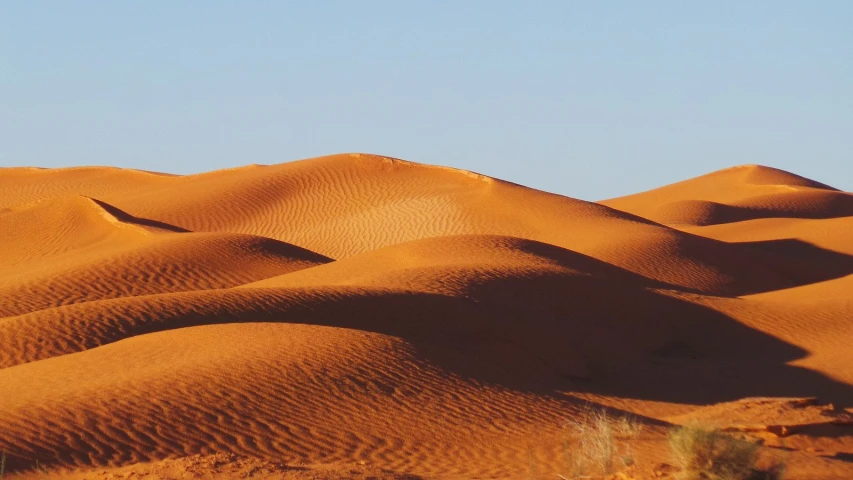 a barren desert with very little clouds in the sky