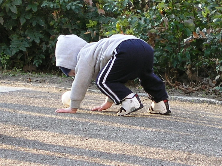 a man crouching down on a road with an object in his hand