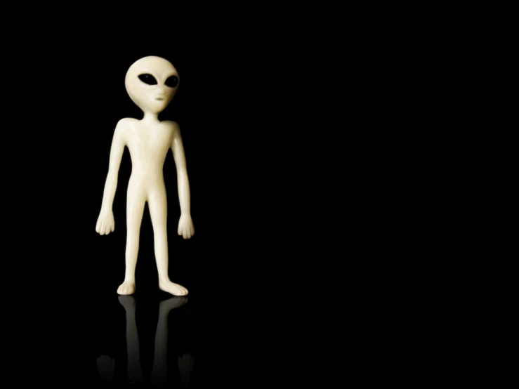 an alien like toy is pictured on a black surface