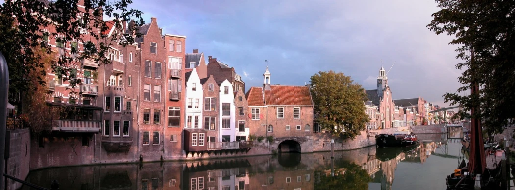 a waterway with boats and houses near an old bridge