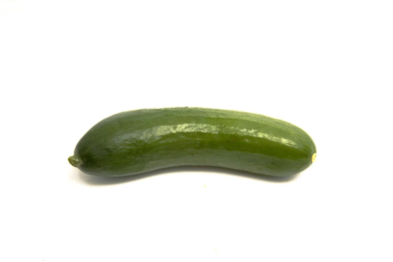 a green cucumber is sitting on a white table