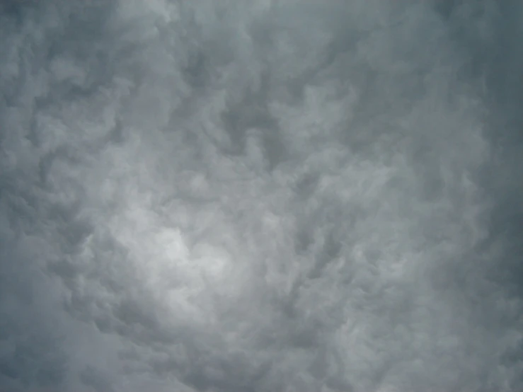 a gray cloudy sky above some water and trees