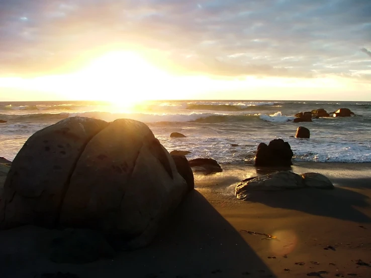 a rock sitting on top of a beach next to the ocean