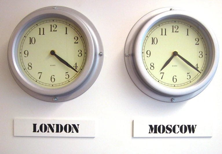 two clocks on a wall have roman numerals