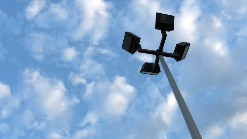 a tall lamp post in front of a blue sky with clouds