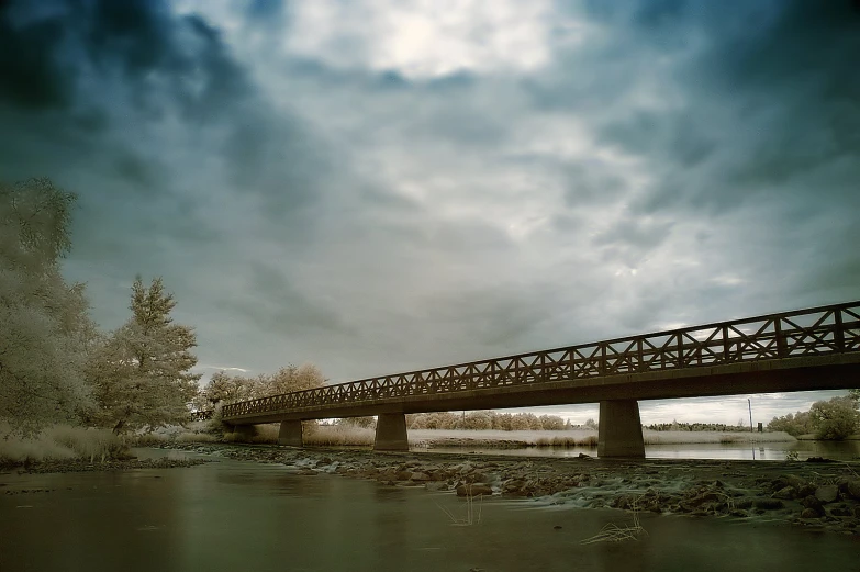 a large bridge over a small river under a cloudy sky