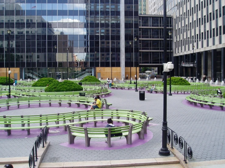 two people sit on benches in an outdoor area in front of buildings