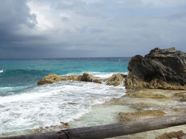 a bench is on the shore near an ocean with waves