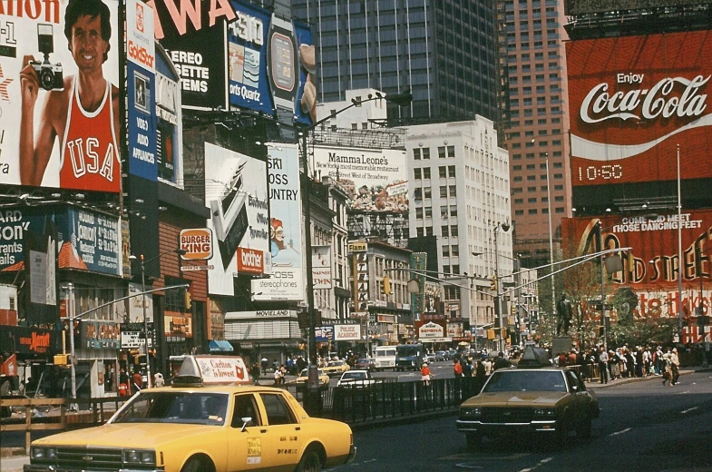 a taxi in the street with several advertits behind it