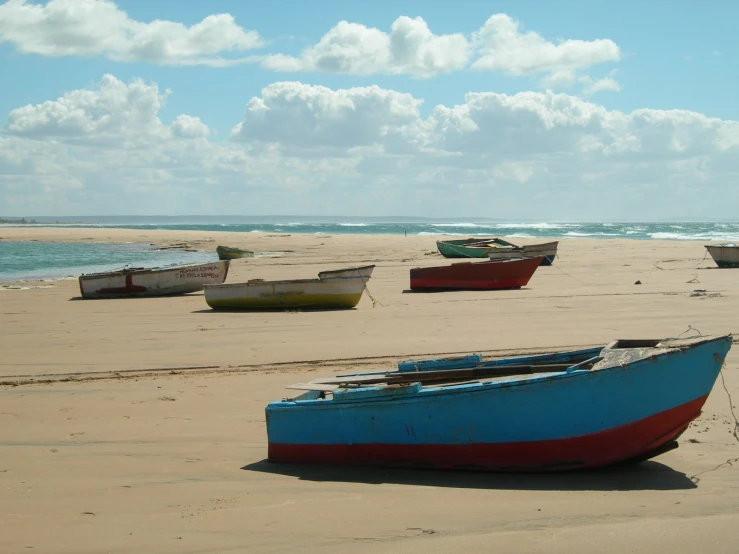 a beach with four small boats sitting on the sand