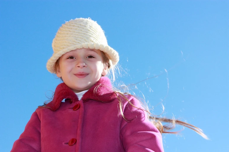 a girl wearing a hat with a blue sky behind her