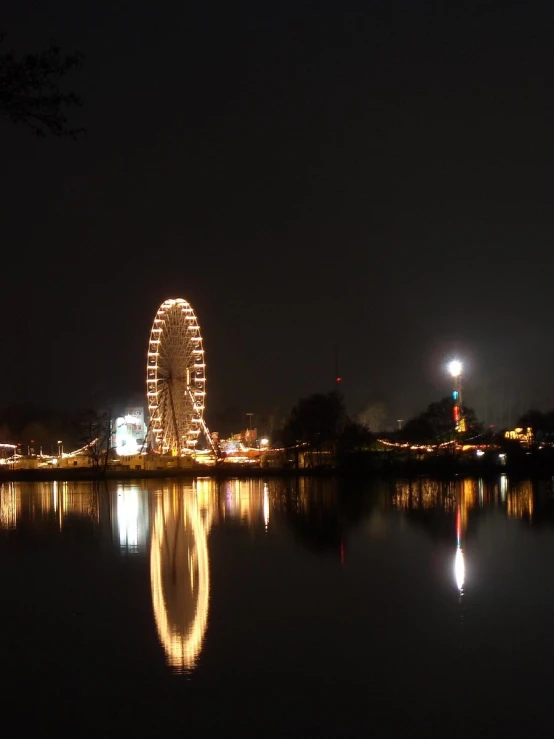 a large ferris wheel in the dark sky above a body of water