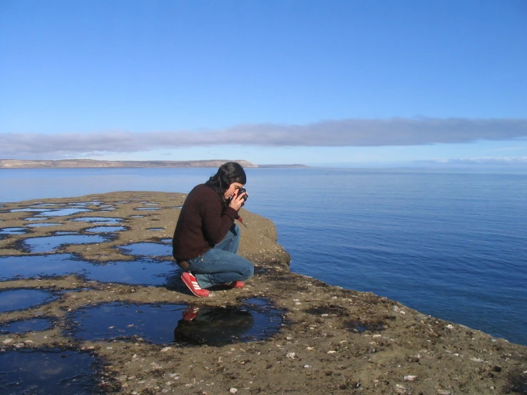 man sitting on the rocks talking on cellphone
