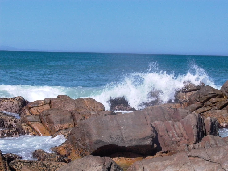 an ocean wave hitting on a rocky shore