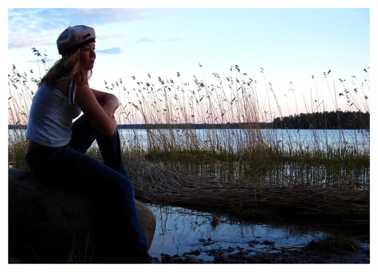 a woman is sitting on the rocks and looking off into the distance