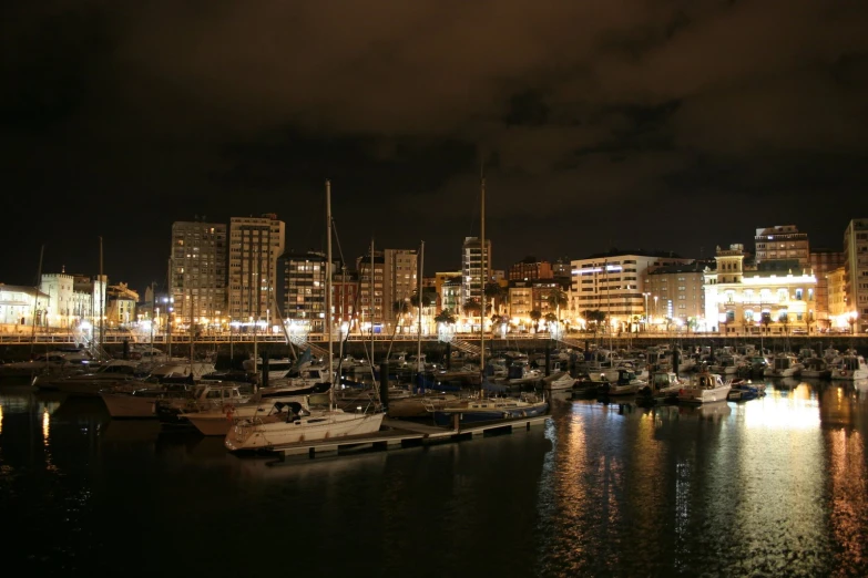 many boats sitting in the harbor next to tall buildings