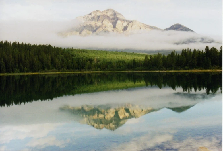 mountains are visible above the calm water of a lake