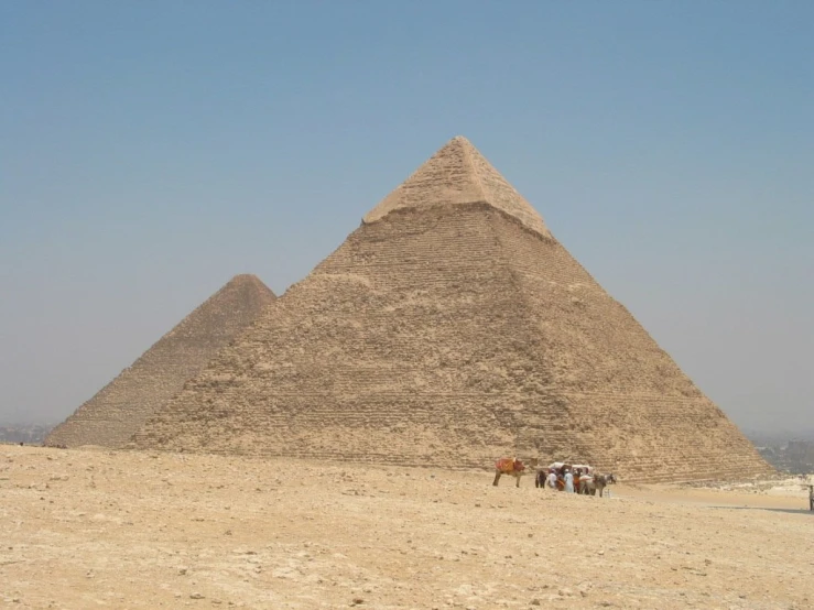 the three horses are outside near the pyramid