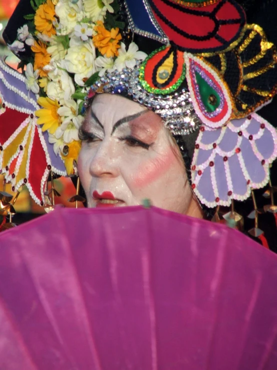 a colorful woman in a costume holding a fan