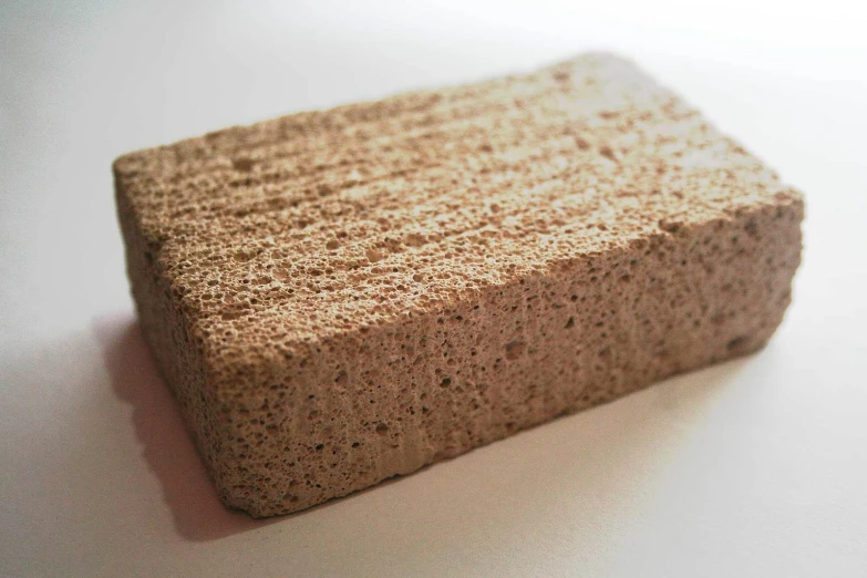 a brown sponge made of concrete on a white surface