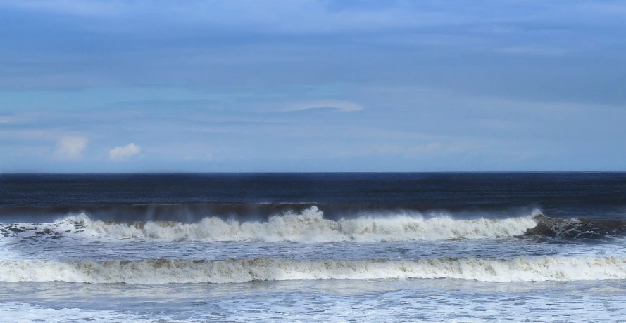 a view of a large ocean wave with blue sky in background