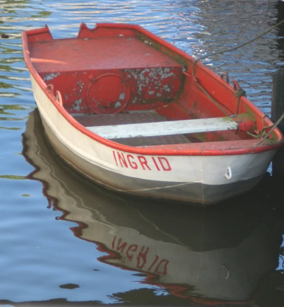 an red and white small boat is parked at the dock