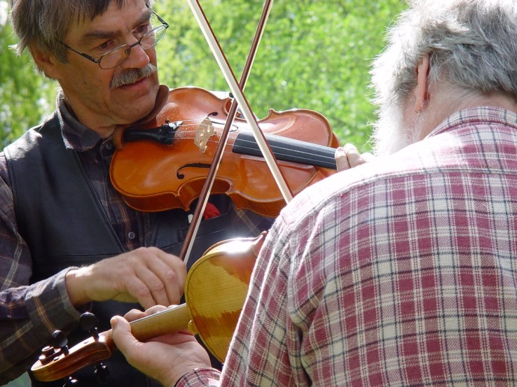 an older man playing violin with an older gentleman