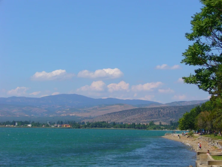 view from the shoreline of a lake with a mountains in the background