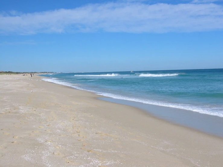 a wide ocean beach with waves coming in from the ocean