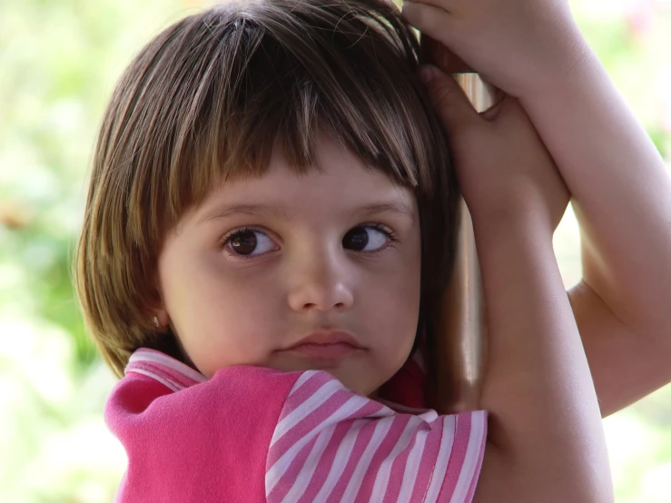 a  holding onto her hair, while she looks down