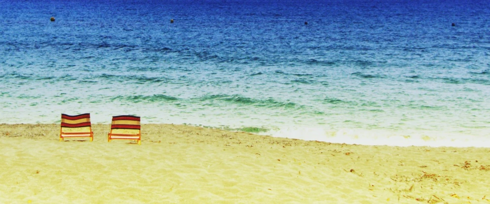 a beach with two empty chairs on it