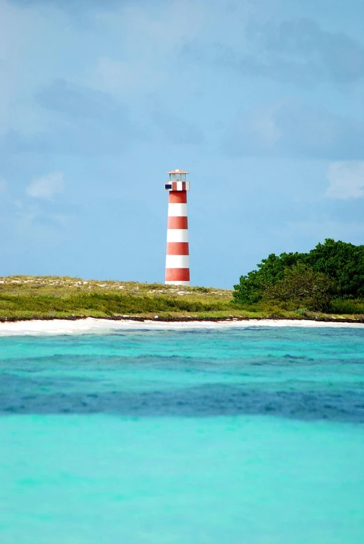 red and white striped lighthouse in the middle of blue water