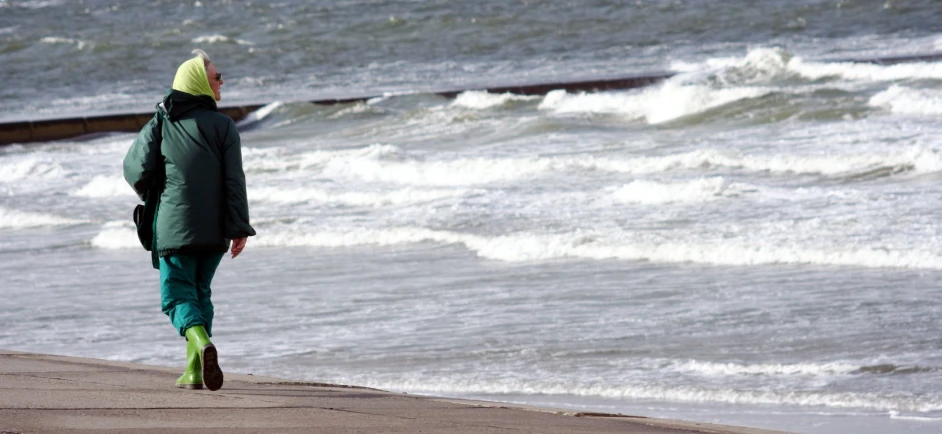 a person with backpack walking on the shore by the ocean