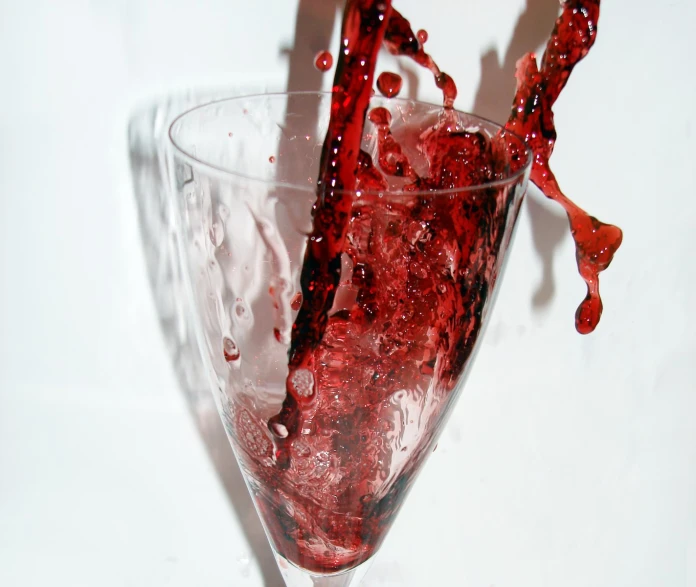 a glass filled with red liquid on a white table